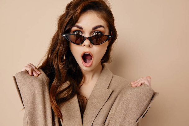 mujer emocional sorprendida mira gafas en la cara y el abrigo beige - Foto, Imagen