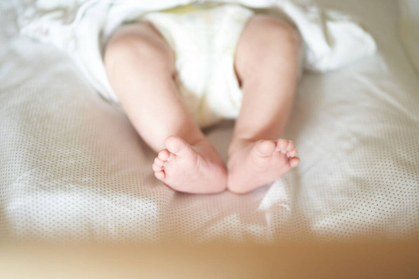 Patas de bebé en sábana blanca, bebé recién nacido 1 mes, cuidado y amor - Foto, imagen