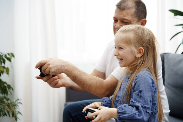 Grandfather and granddaughter playing video games at home. - Fotografie, Obrázek