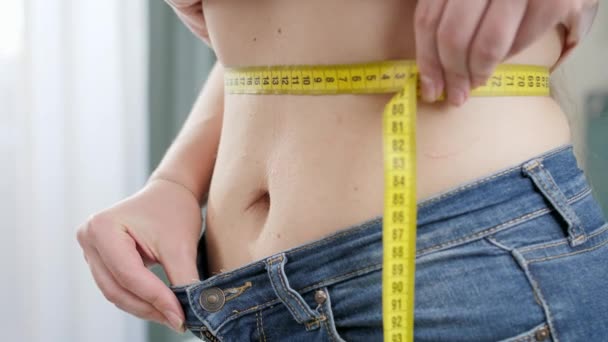 CLoseup van jonge vrouw meten haar taille na het verliezen van gewicht. Concept van dieet, afvallen en gezonde levensstijl. - Video