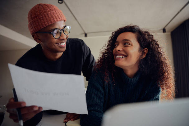 Close up of mixed race couple using laptop for online banking. Happy African American couple smiling and looking at each other while working together at home. High quality photo - Foto, Imagen