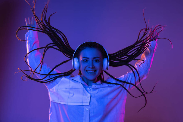 Caucasian young womans portrait on dark studio background in neon. Concept of human emotions, facial expression. - Фото, зображення
