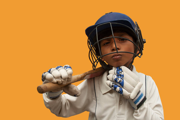Retrato de niño usando casco de cricket y sosteniendo murciélago - Foto, imagen