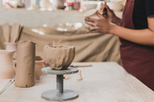 vista de cerca de olla de arcilla hecha a mano cerca borrosa joven afroamericana en primer plano en cerámica - Foto, Imagen