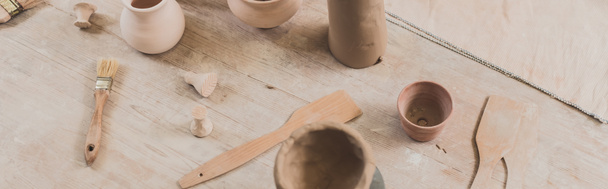 陶器の木製テーブルの上にへらを持つ手作りの粘土鍋の高い角度ビュー,バナー - 写真・画像