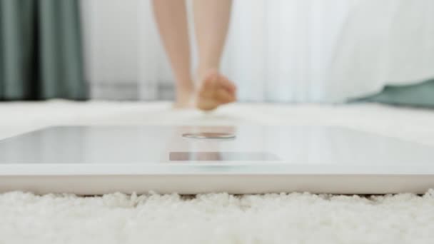 Joven mujer descalza de pie en balanzas digitales para medir su peso. Concepto de dieta, adelgazamiento y estilo de vida saludable. - Imágenes, Vídeo