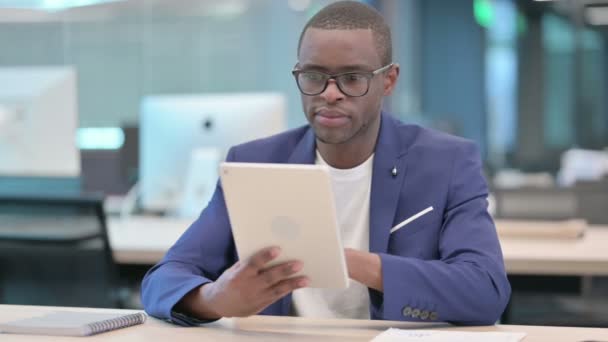 Attrayant homme d'affaires africain en utilisant la tablette dans le bureau  - Séquence, vidéo