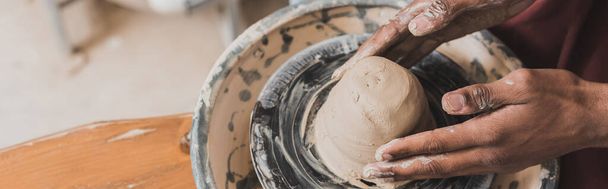 крупним планом вид молодого афроамериканця, що моделює мокру глину на колесі в кераміці, банер
 - Фото, зображення