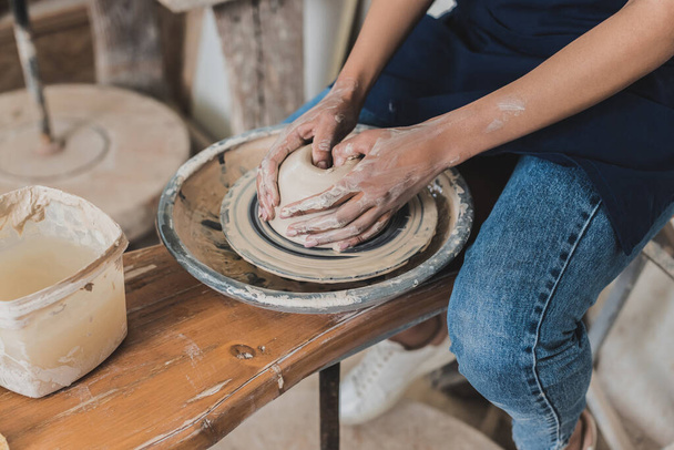 visão parcial da jovem afro-americana modelando argila molhada na roda com as mãos em cerâmica - Foto, Imagem