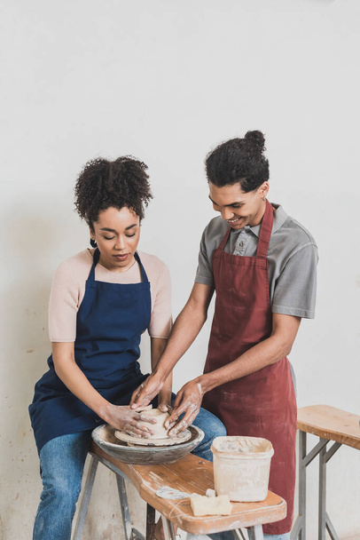 happy young african american couple modeling wet clay on wheel with hands in pottery - Fotoğraf, Görsel