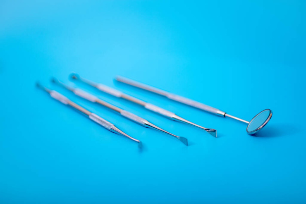 Set of Dentist's medical equipment tools. Stainless steel dental equipment on blue background with copy space. - Fotografie, Obrázek