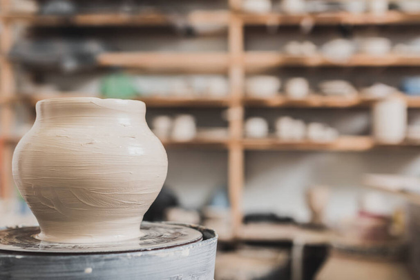 olla de barro mojado en la rueda de cerámica en el banco de madera en el estudio de arte - Foto, Imagen
