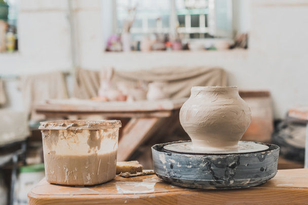 sculpted wet clay pot on pottery wheel on wooden table in art studio - Fotografie, Obrázek