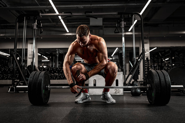 Athlete, bodybuilder exercise with a barbell, athlete prepares the barbell for exercise, beautiful body, healthy lifestyle - 写真・画像