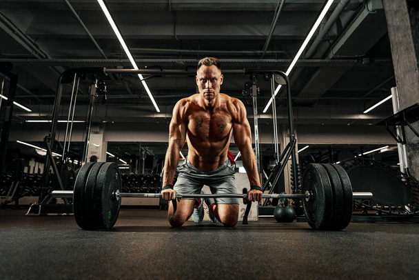 Young shirtless man doing deadlift exercise at gym. Screaming for motivation - Photo, Image