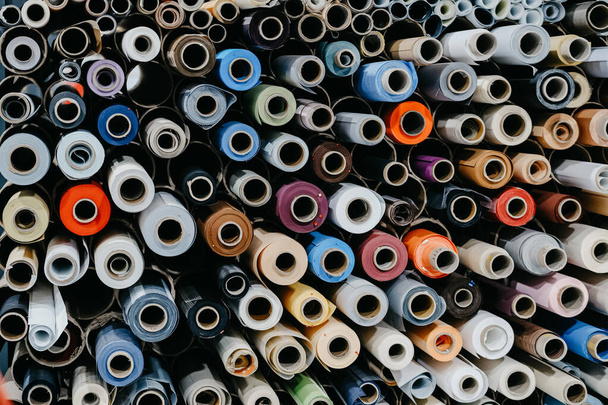 A closeup of rolls of colorful textile and fabric for roller blinds in a factory - Photo, Image
