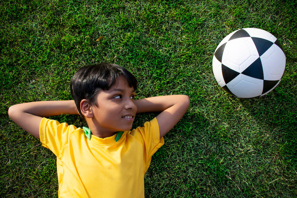 Fiatal fiú feküdt a földben a focival - Fotó, kép