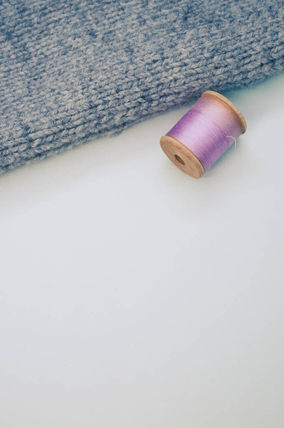 A purple sewing thread beside a grey fabric on a white background with free space for text - Фото, зображення
