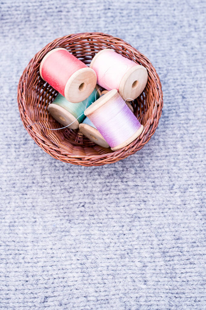 A basket of colorful sewing threads on a grey fabric with free space for text - Valokuva, kuva
