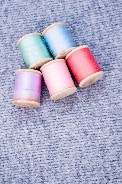 A colorful sewing threads on a grey fabric with free space for text - Φωτογραφία, εικόνα