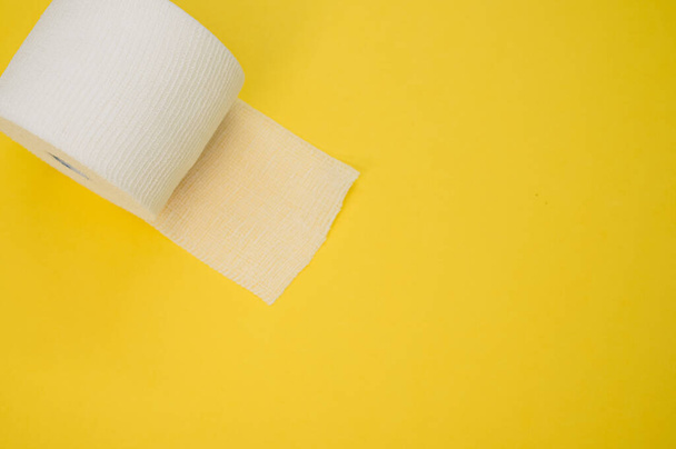 a top view of a sterile gauze bandage roll isolated on a yellow background on the left side - Fotoğraf, Görsel