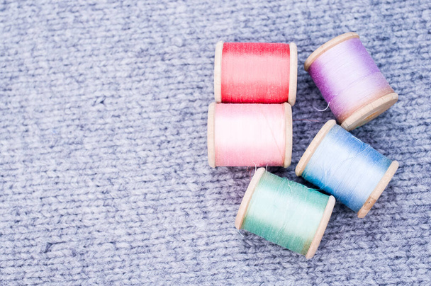 A colorful sewing threads on a grey fabric with free space for text - Φωτογραφία, εικόνα