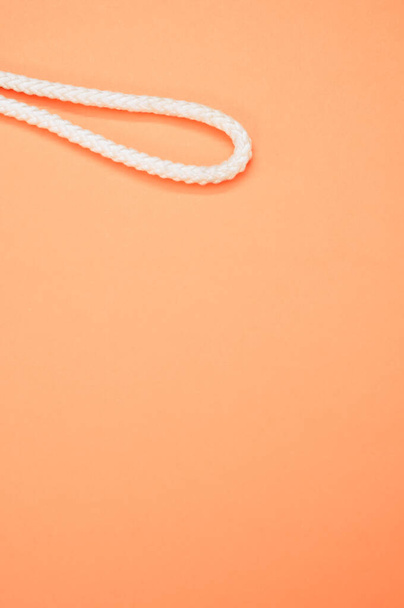 A vertical shot of a white rope part isolated on a peach color background - Foto, Bild