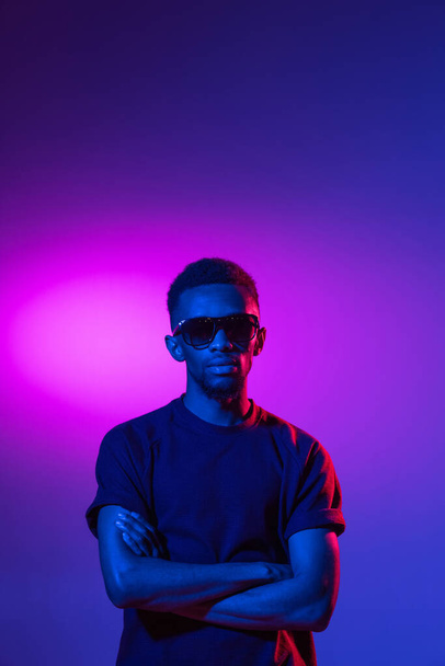 African-american young mans portrait on dark studio background in neon. Concept of human emotions, facial expression, youth, sales, ad. - Fotoğraf, Görsel