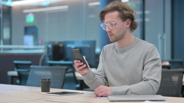 Vonzó fiatal üzletember használja Smartphone az irodában  - Felvétel, videó