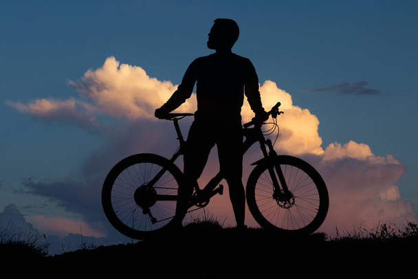 Conquistar picos de montaña por ciclista en pantalones cortos y jersey en una moderna bicicleta rígida de carbono con una horquilla de suspensión neumática. Hermosa vista desde la montaña. - Foto, Imagen