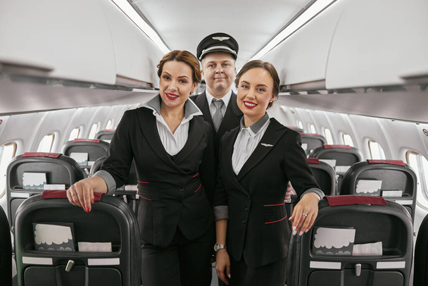 Piloto y azafatas en cabina de pasajeros del avión - Foto, Imagen
