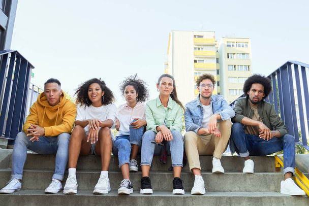 Група молодих людей, що сидять поспіль на сходах
 - Фото, зображення