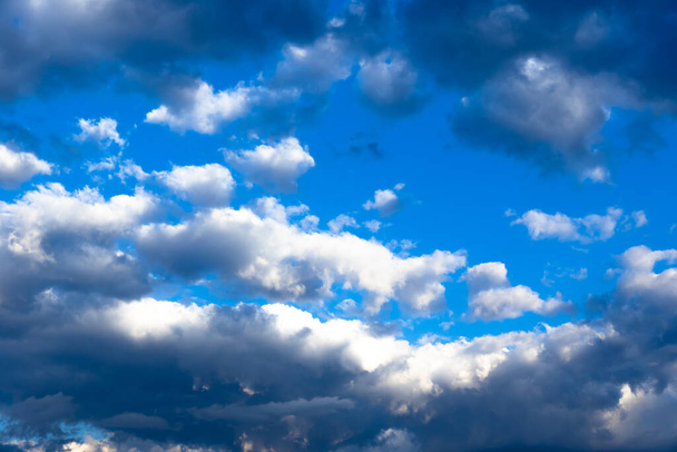 Des nuages gris se rassemblent dans le ciel bleu un jour d'été. Plusieurs nuages sont blancs. Plan d'ensemble - Photo, image