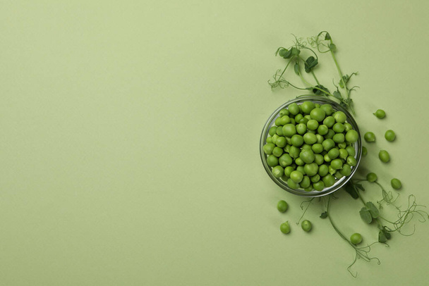 Bowl with pea seeds on green background - Fotoğraf, Görsel