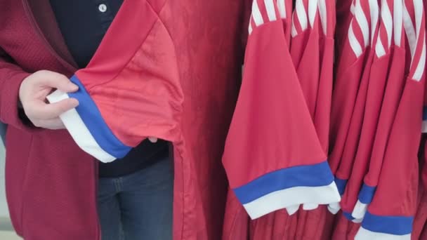 Mujer en tienda elige camisa para deportes con impresión de la bandera de Rusia - Metraje, vídeo
