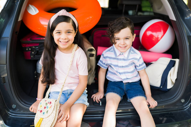 No podemos esperar a llegar a la playa. Adorable hermanito y hermana esperando a sus padres en el coche mientras empacan sus cosas para comenzar sus vacaciones familiares - Foto, imagen