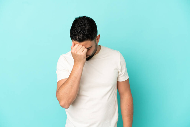 Young arab man isolated on blue background with headache - Foto, afbeelding