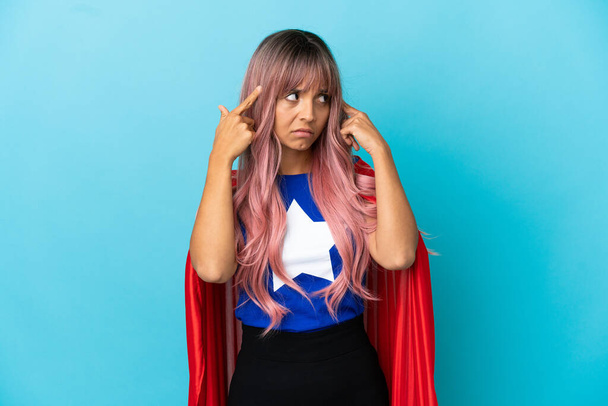 Jeune femme super-héros aux cheveux roses isolé sur fond bleu ayant des doutes et pensant - Photo, image