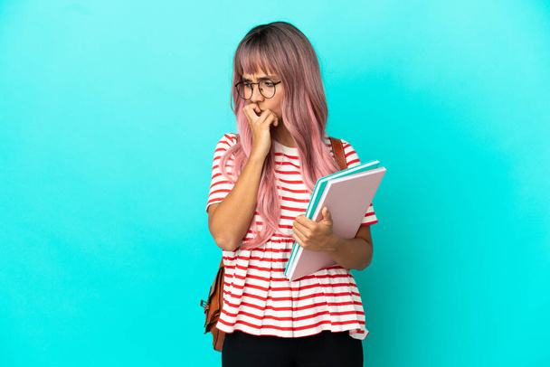 Giovane studentessa con i capelli rosa isolato su sfondo blu avendo dubbi - Foto, immagini