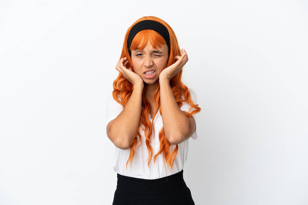 Nuori nainen oranssi hiukset eristetty valkoisella taustalla turhautunut ja kattaa korvat - Valokuva, kuva
