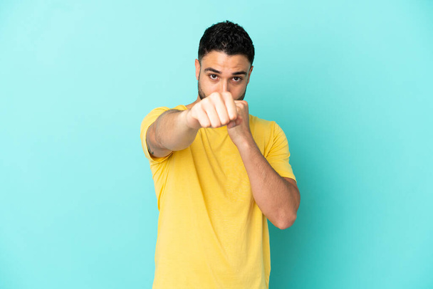 Young arab man isolated on blue background with fighting gesture - Foto, Bild