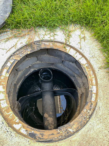 Un tubo negro en un estanque de tratamiento de residuos está enterrado bajo tierra en la casa. - Foto, imagen