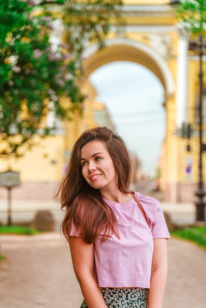 Милая туристка в Санкт-Петербурге на фоне желтой арки с красивой архитектурой, туристический летний сезон - Фото, изображение