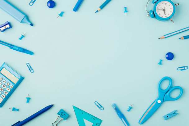 Top view photo of school supplies blue papeteria on isolated pastel blue background with copyspace in the middle - Zdjęcie, obraz