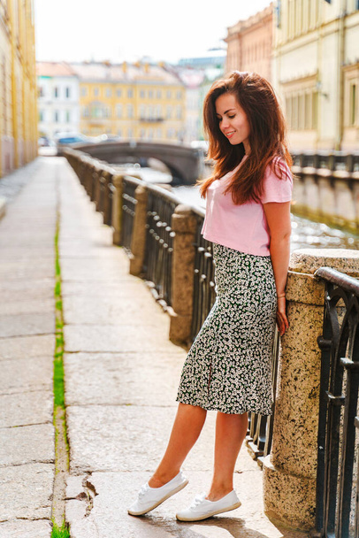 Una bella giovane donna passeggia per il centro della città lungo i canali in una giornata estiva, una popolare destinazione turistica di San Pietroburgo. - Foto, immagini
