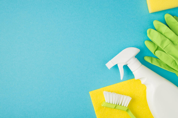 Πάνω φωτογραφία του σπρέι βούρτσα καθαρισμού σαπούνι κουρέλι και πράσινα γάντια που απομονώνονται στο μπλε φόντο - Φωτογραφία, εικόνα