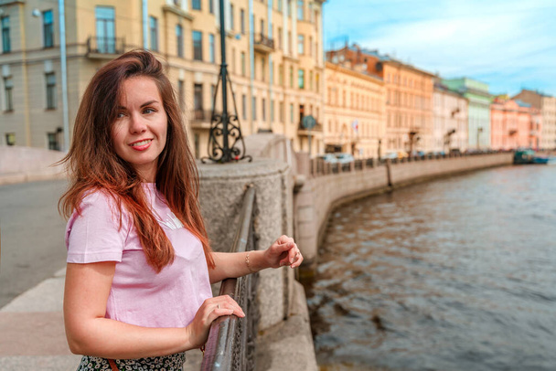 A beautiful young woman walks through the city center along the canals on a summer day, a popular tourist destination of St. Petersburg - Foto, immagini