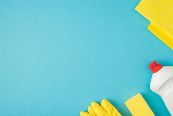 Foto aérea de jabón limpiador detergente de trapo y guantes amarillos aislados en el fondo azul - Foto, Imagen