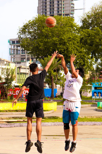 2 asian men are jumping to aim the basket ball that has been thrown to the air. As soon as they reach the basketball, the game will begin - Fotografie, Obrázek