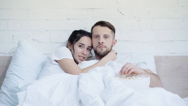 scared woman watching movie with boyfriend near popcorn bowl - Valokuva, kuva